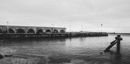 Grayscale Photo of Body of Water Near White Concrete Wall