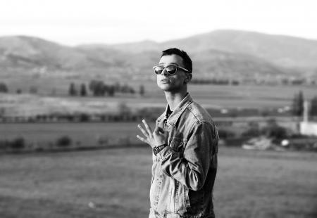 Grayscale Photo of Man Wearing Denim Jacket Near Mountain at Daytime