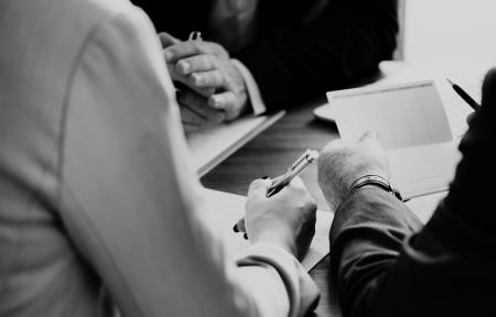 Grayscale Photo of Three Person Sitting Near Table