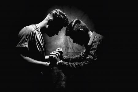 Grayscale Photo of Two Men Holding Hands