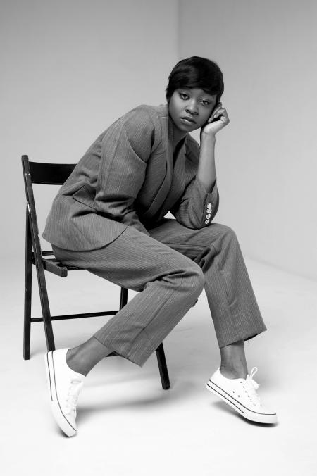 Grayscale Photo of Woman in Formal Suit Sitting on Folding Chair