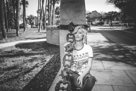 Grayscale Photo of Woman Leaning on Concrete Post