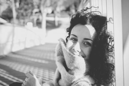 Grayscale Photo of Woman Leaning on White Pole