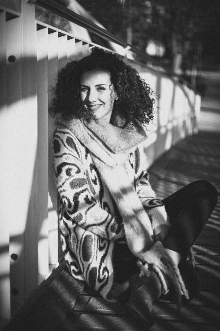 Grayscale Photo of Woman Sitting on Bridge