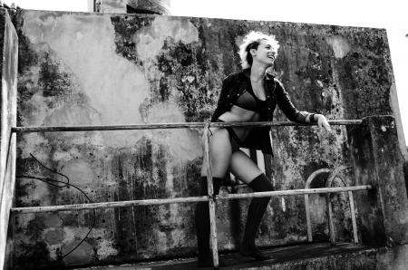 Grayscale Photo of Woman Smiling Holding on Rail