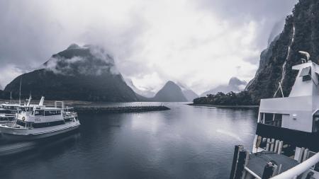 Grayscale Photo of Yachts on Body of Water Under Cloudy Sky