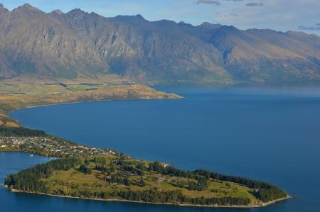 Green Field Island in the Middle of Body of Water Near Mountains during Daytime