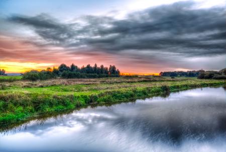 Green Field Near Body of Water during Daytime