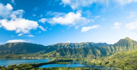 Green Forested Mountain Range Under Blue Sky With Clouds