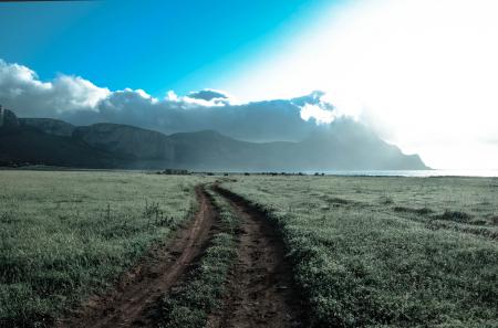 Green Grass Field Beside Brown Mountains Under White Cloudy Sky