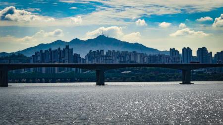 Grey Concrete Bridge Near Cities and Mountain at Daytime