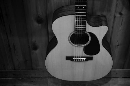 Greyscale Photo of Acoustic Guitar on Wooden Fence