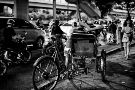 Greyscale Photo of Man Sitting On Sidecar oF Bicycle