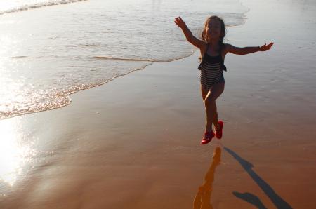 Happy girl jumping on the beach at dawn