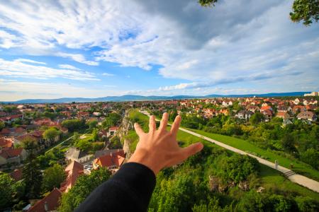 Human Hand Under White and Blue Sky on Green Grass Field