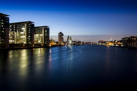 Landscape Photo of High Rise Lightning Building Near Body of Water during Night Time