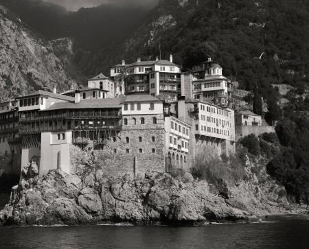 Landscape Photography of Gray and White House Near Mountain Cliffs Above Body of Water