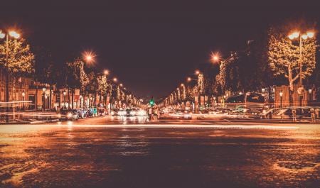 Lighted Street With Cars Passing by during Nighttime