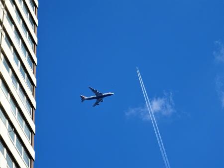 Low-angle Photography of White Plane on Mid-air Near White Concrete Building and White Contrail