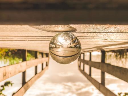 Macro Photography of Round Glass Ball on Top of Brown Wooden Dock