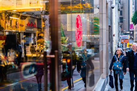 Man and Woman Passing Through Building With Glass Facade