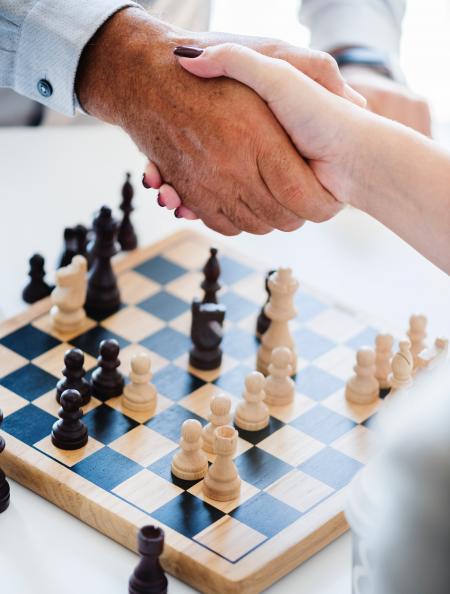 Man and Woman Shaking Hands over a Game of Chess