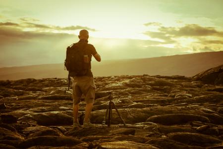 Man Beside Tripod on Rocks during Golden Hour
