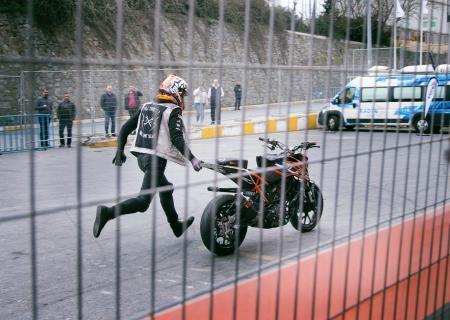 Man Holding Orange and Black Sports Bike on Asphalt Road