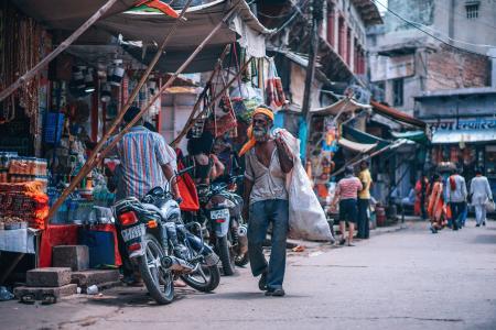 Man Holding White Sack Walking Beside Street Stores