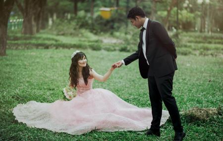 Man in 2-piece Suit Holding Woman in Peach-colored Wedding Gown White Holding Her Flower Bouquet