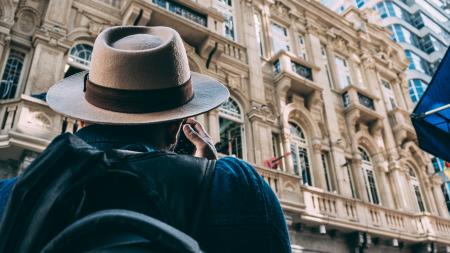 Man in Beige Hat Taking Picture on Beqige Conrete Architectural Building