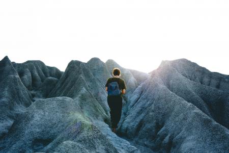 Man in Black Crew Neck Shirt and Pants Walking on Gray Mountain Formations