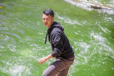 Man in Black Hoodie Standing in Front of Body of Water