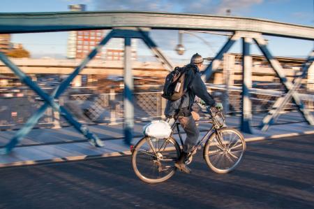 Man in Black Jacket Riding Black Bicycle in Gray Concrete Road in Panning Photography