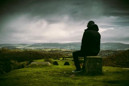 Man in Black Jacket Sitting on Block