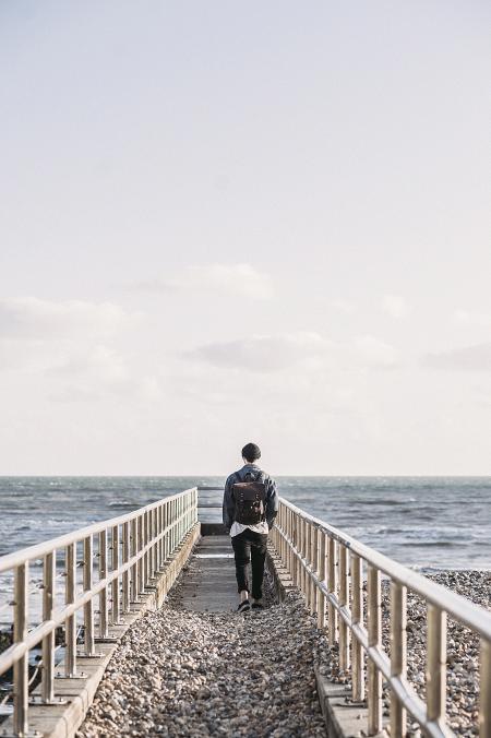 Man in Black Jacket Walking on Gray Concrete Dock