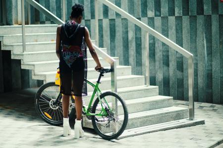 Man in Black Sleeveless Shirt Holding Green Mountain Bike Near Metal Staircase