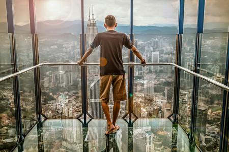 Man in Black T-shirt Looking Out of Glass Windows during Sunset