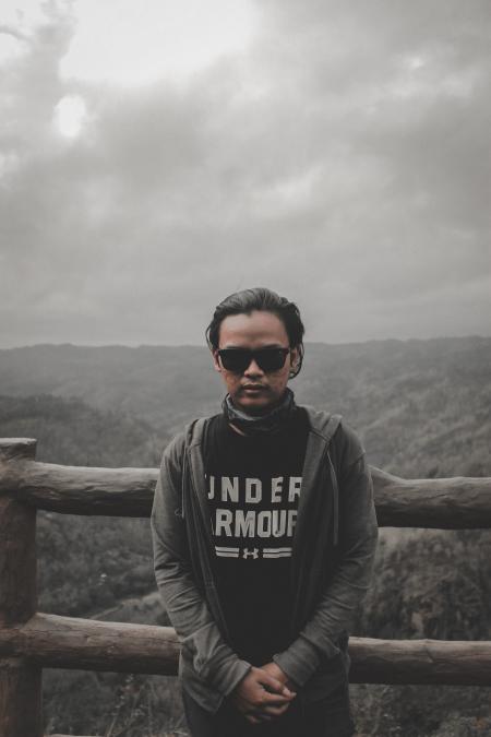 Man in Black Top and Grey Hoodie Jacket Standing Beside Brown Wooden