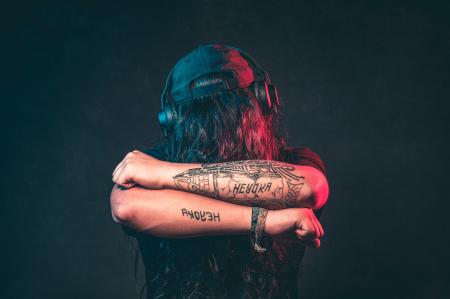 Man in Black Top Wearing Headphones Showing His Tattoos