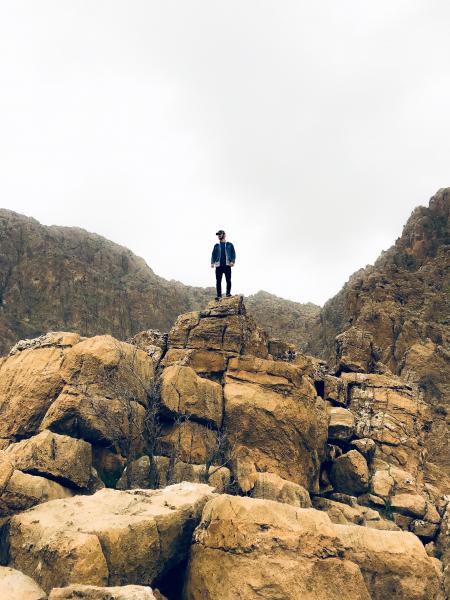 Man in Denim Jacket and Black Bottom Standing on Brown Concrete Stone