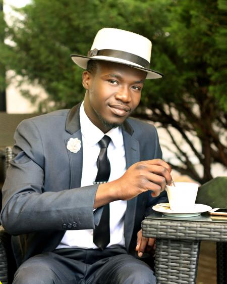 Man in Gray Formal Suit Jacket Stirring Coffee during Daytime