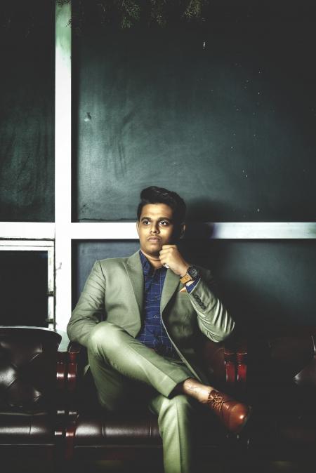 Man in Gray Notch-lapel Suit Jacket With Dress Pants While Sitting on Armchair