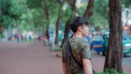 Man in Green and Grey Camouflage Shirt While Standing Behind Tree