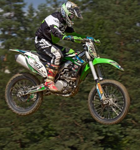 Man in Green White and Black Mtx Suit on Green and White 303 Dirt Motorcycle in the Air