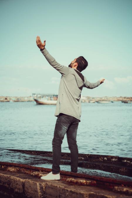 Man In GrEy Hoodie Standing on Grey Pavement Near Sea