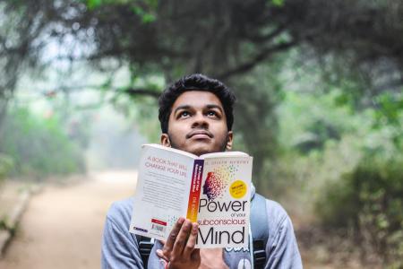 Man in Grey Shirt Holding Opened Book Looking Upward