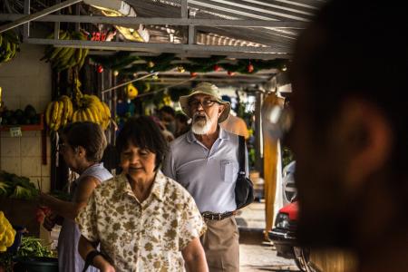 Man in Purple Polo Shirt and Brown Hat Behind Woman in Brown and White Floral Button-up T-shirt