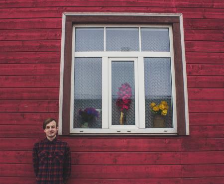 Man in Red and Black Dress Shirt Standing Beside a Red Wall