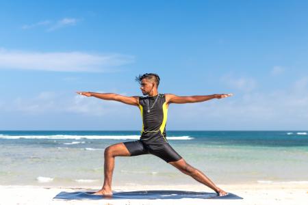Man in Sleeveless Wet Suit Doing Some Aerobics at the Beach